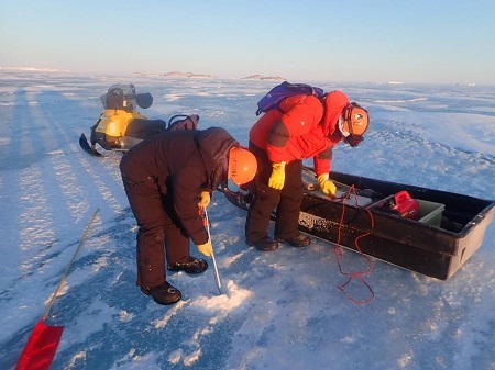ドリルで海氷に穴を開けて氷圧を測定している様子